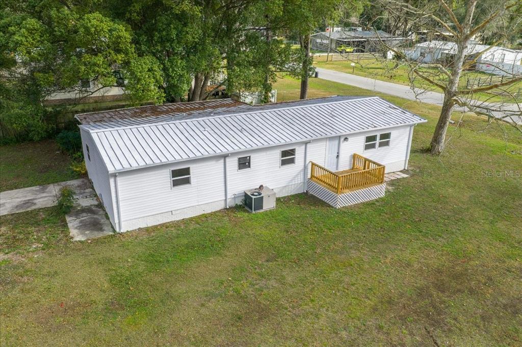 An aerial view shows a white single-story house with a metal roof and wooden deck — 13219 32ND COURT, BELLEVIEW, FL