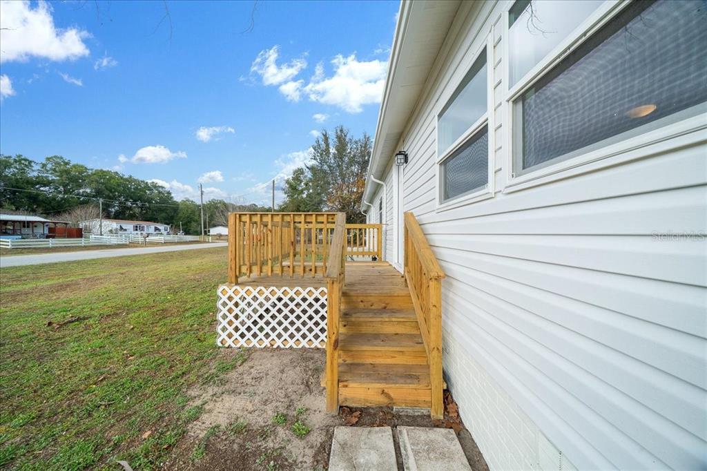 A wooden deck with stairs and lattice skirting is attached to the side of a house — 13219 32ND COURT, BELLEVIEW, FL