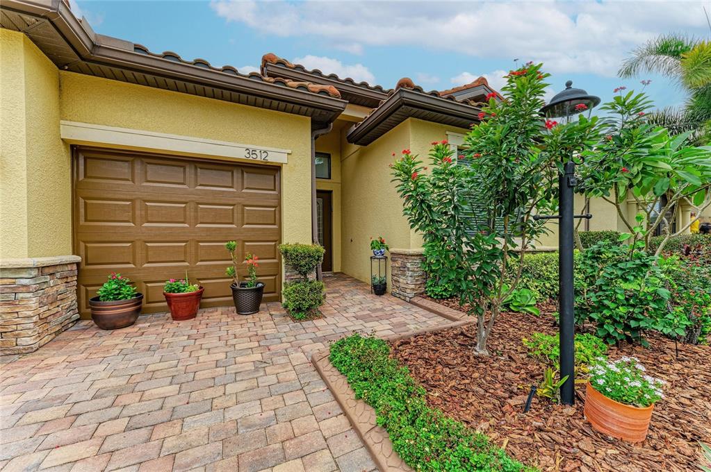A paved driveway leads to a garage and front entrance of a stucco house — 3512 SAVANNA PALMS COURT, BRADENTON, FL
