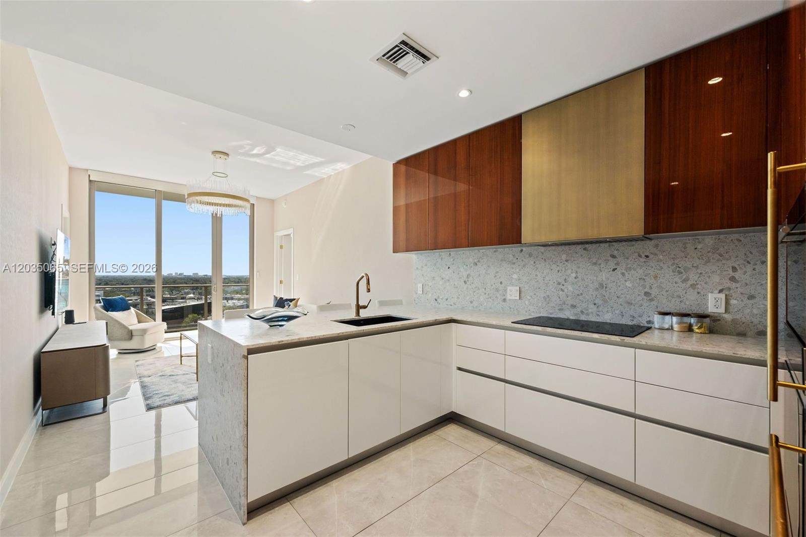 A modern kitchen features white cabinetry, a terrazzo backsplash, and a view of the outdoors — 2678 Tigertail Ave # 1705, Miami FL 33133, MIAMI, FL