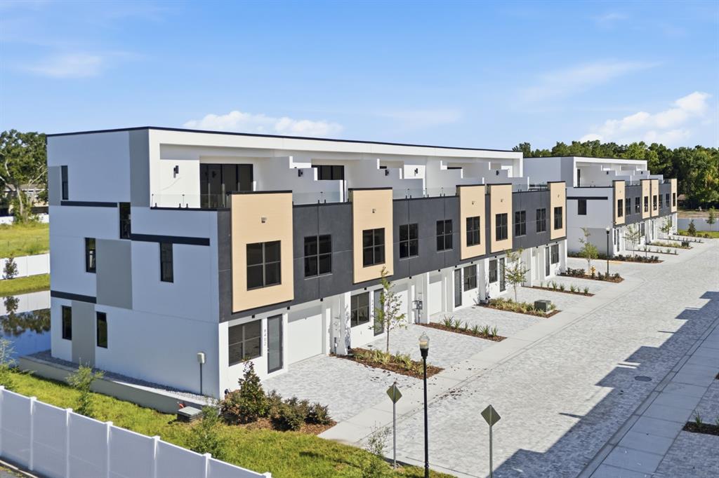 An exterior view of a modern multi-unit townhouse complex with white and dark gray siding — 8405 MODANO PLACE, TAMPA, FL