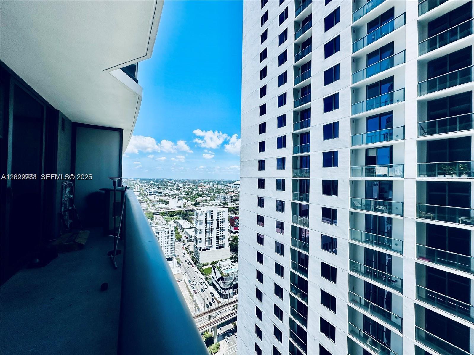 A high-rise balcony overlooks a city street and an adjacent residential tower — 55 SW 9th St # 3409, Miami FL 33130, MIAMI, FL