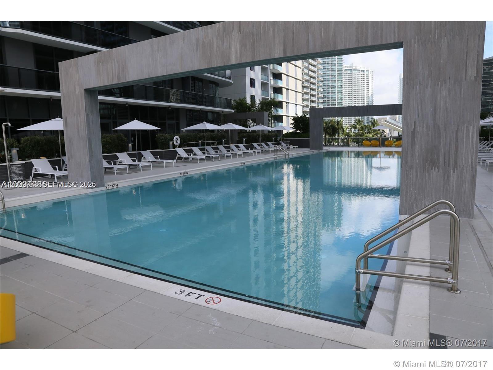 An outdoor swimming pool with lounge chairs and a modern concrete frame structure — 55 SW 9th St # 3409, Miami FL 33130, MIAMI, FL