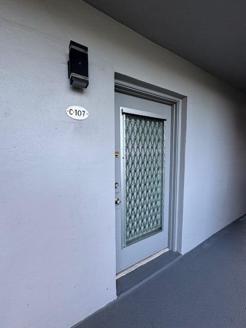 An exterior view of a gray door labeled C-107 with a patterned glass insert — 107 Flanders, Delray Beach FL 33484, DELRAY BEACH, FL