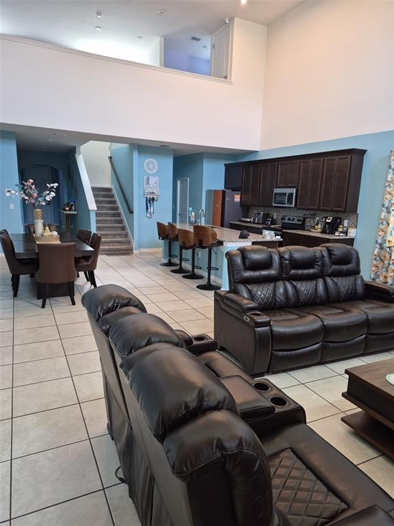 An open-concept living area features a kitchen with dark cabinets, a dining space, and stairs — 1490 FLATWOOD STREET, ST CLOUD, FL