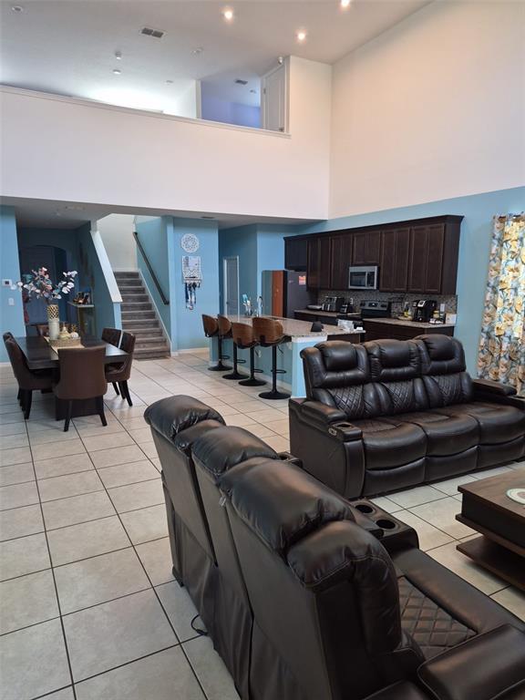 An open-concept living area features a kitchen with dark cabinets, a dining table, and stairs — 1490 FLATWOOD STREET, ST CLOUD, FL