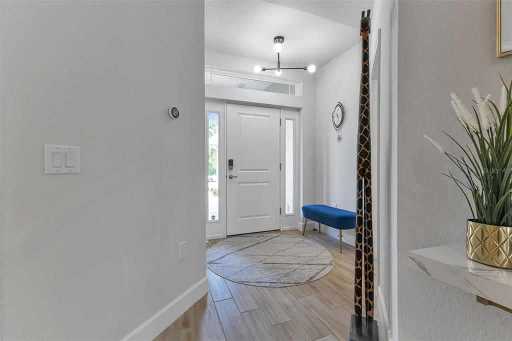An entryway features a white front door, a blue bench, and a tall giraffe sculpture — 7664 MERONI BOULEVARD, NORTH PORT, FL
