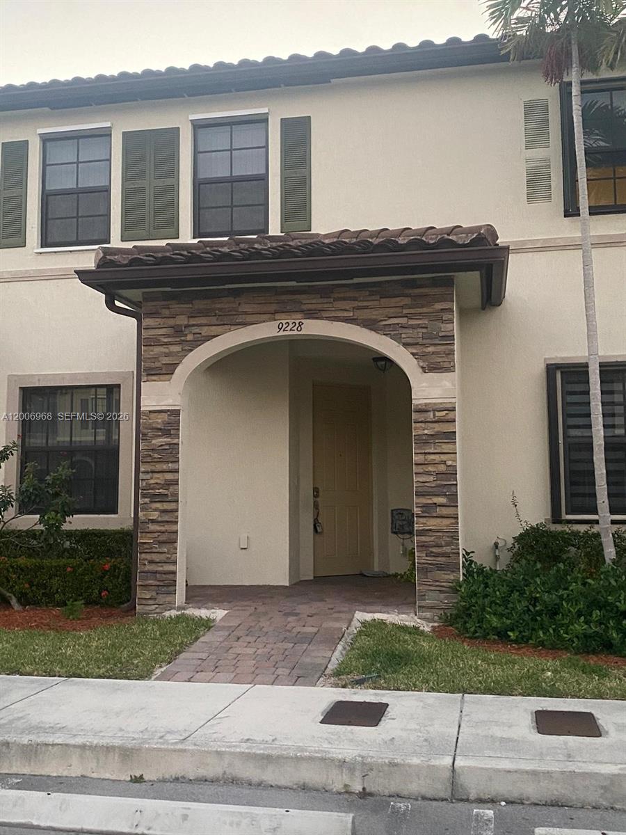 The exterior of a two-story townhouse features a stone-accented arched entryway and tan siding — 9228 W 33rd Way # 9828, Hialeah FL 33018, HIALEAH, FL