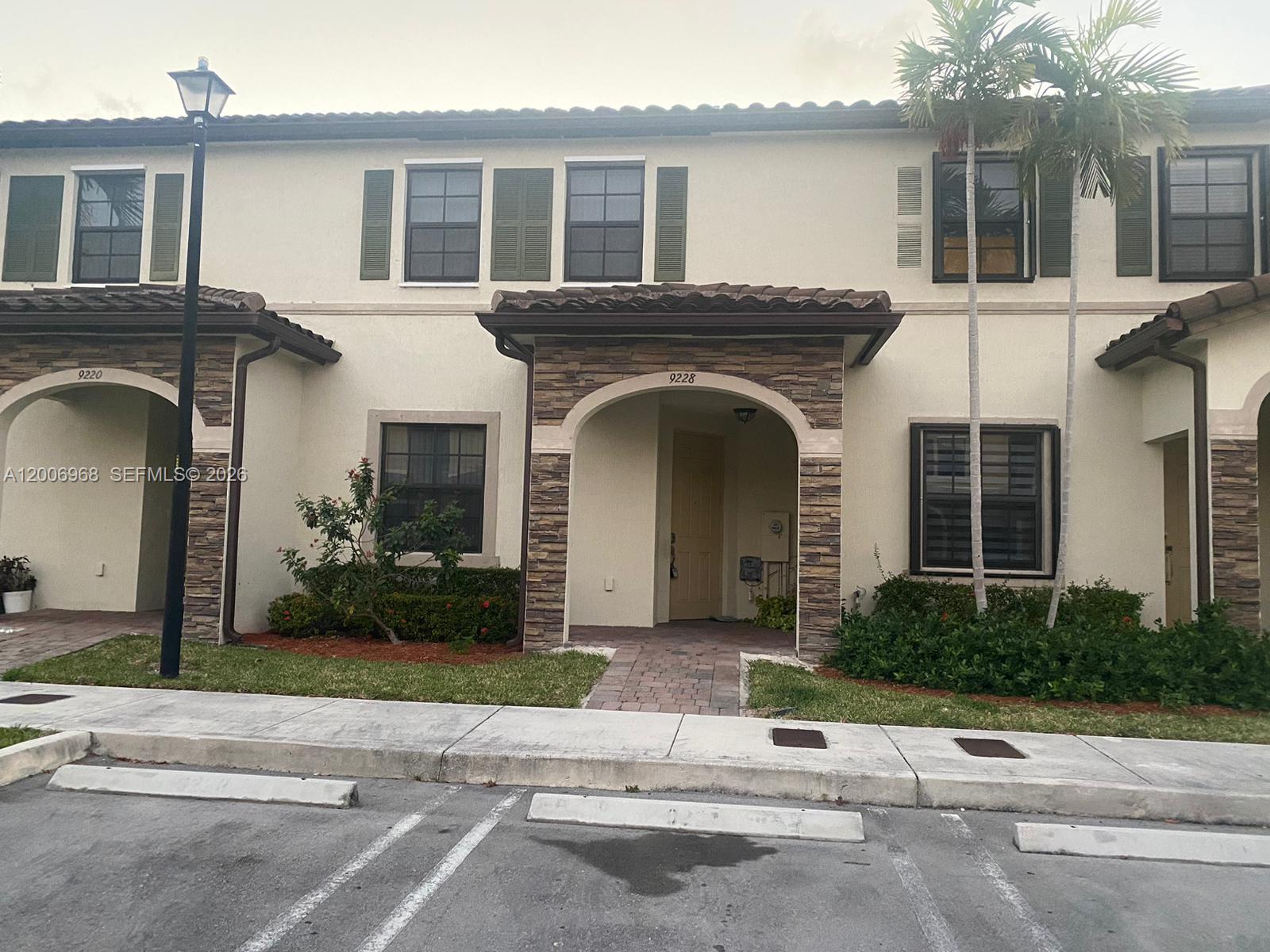 A two-story townhouse exterior features a stone-accented arched entryway and a paved walkway — 9228 W 33rd Way # 9828, Hialeah FL 33018, HIALEAH, FL