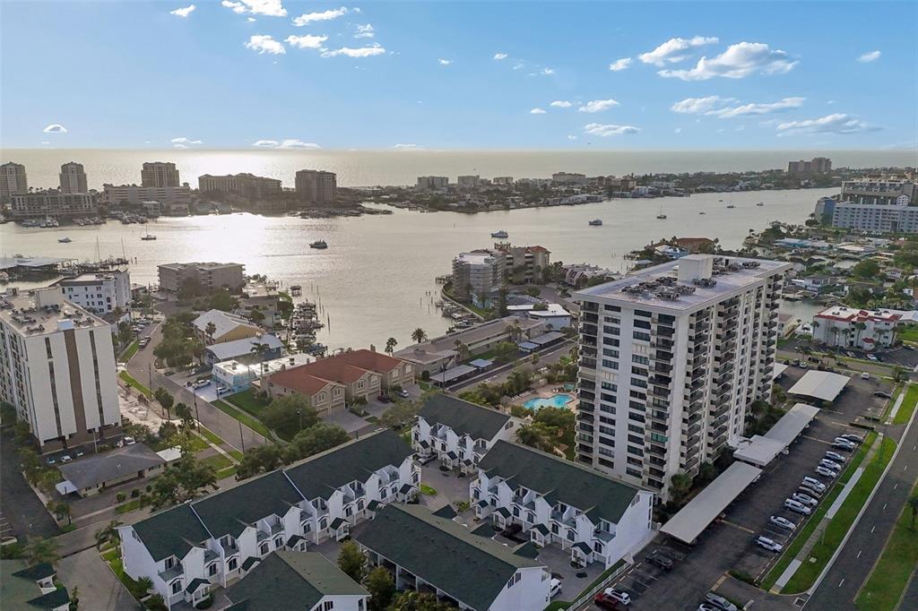 An aerial view shows a coastal residential area with a high-rise building and townhomes — 320 ISLAND WAY UNIT 304, CLEARWATER BEACH, FL