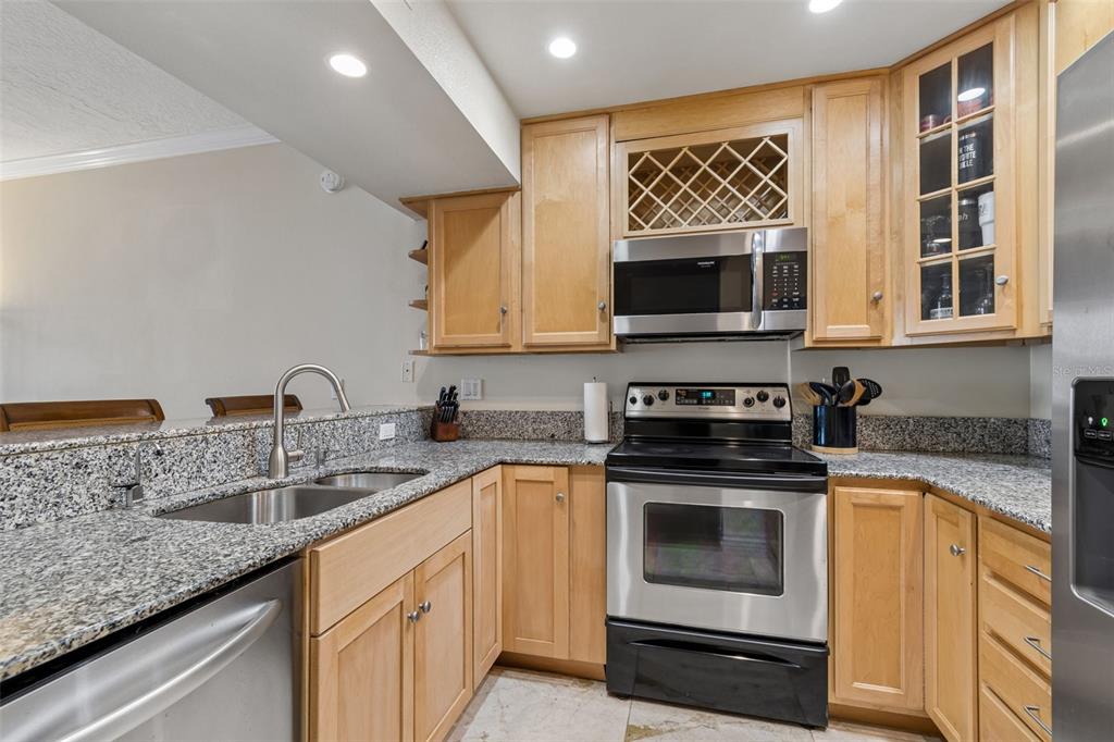 A kitchen with light wood cabinets, granite countertops, and stainless steel appliances — 320 ISLAND WAY UNIT 304, CLEARWATER BEACH, FL