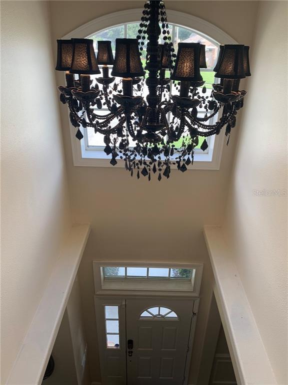 A high-angle view of an entryway featuring a large black chandelier and a front door — 1630 TAWNYBERRY COURT, TRINITY, FL