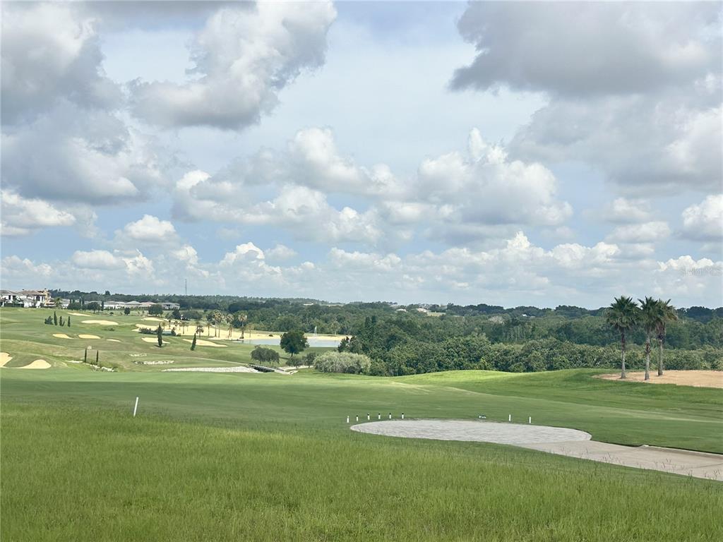 A view of a golf course with a paved tee box and distant water feature — 16243 VETTA DRIVE, MONTVERDE, FL