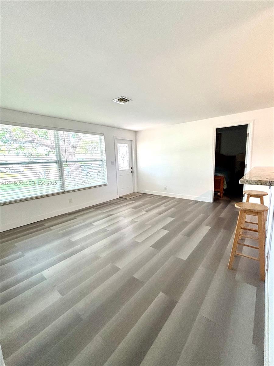 This living area features light gray wood-look flooring, white walls, a large window, and stools — 5809 Sullivan Rd, Jupiter FL 33458, JUPITER, FL