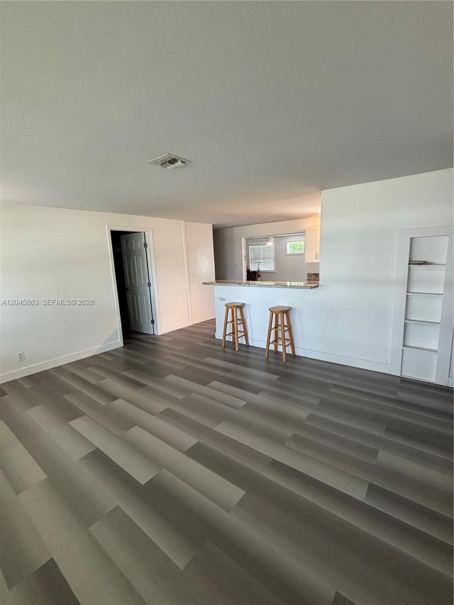 A living room features gray wood-look flooring, a breakfast bar with stools, and built-in shelving — 5809 Sullivan Rd, Jupiter FL 33458, JUPITER, FL