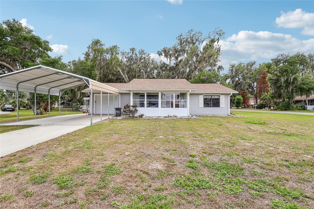 A single-story house with gray siding, a metal carport, and a large front yard — 931 CR 457A, LAKE PANASOFFKEE, FL