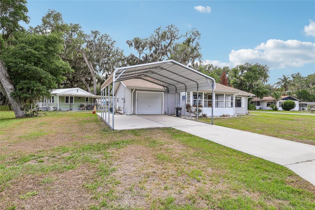 A single-story house with a metal carport over a concrete driveway and a screened porch — 931 CR 457A, LAKE PANASOFFKEE, FL