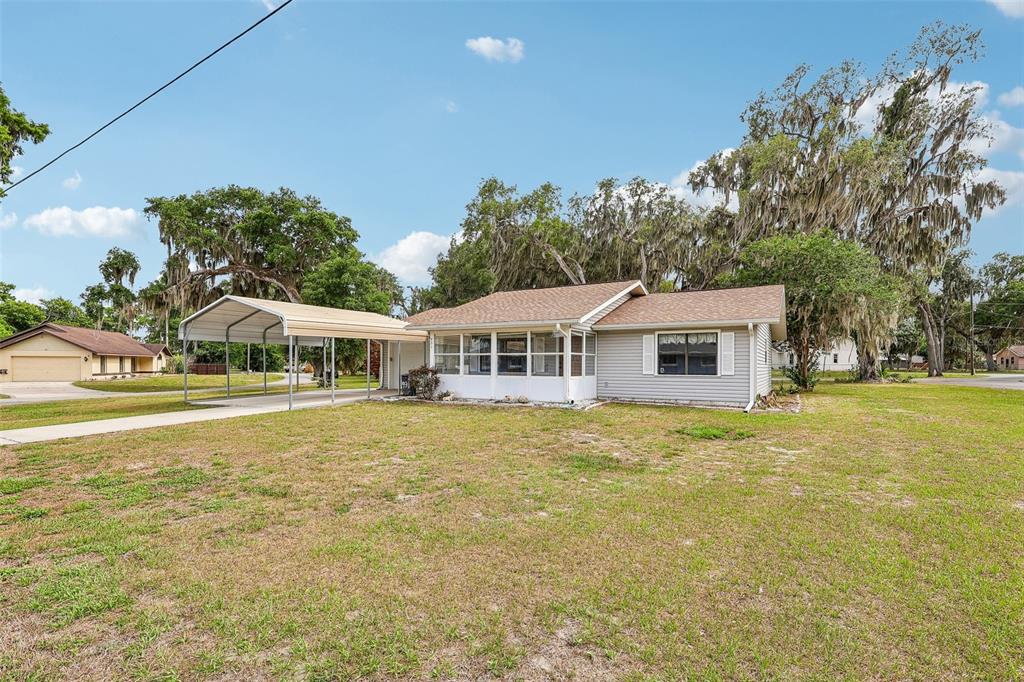 A single-story house with light gray siding, a screened-in porch, and a metal carport — 931 CR 457A, LAKE PANASOFFKEE, FL