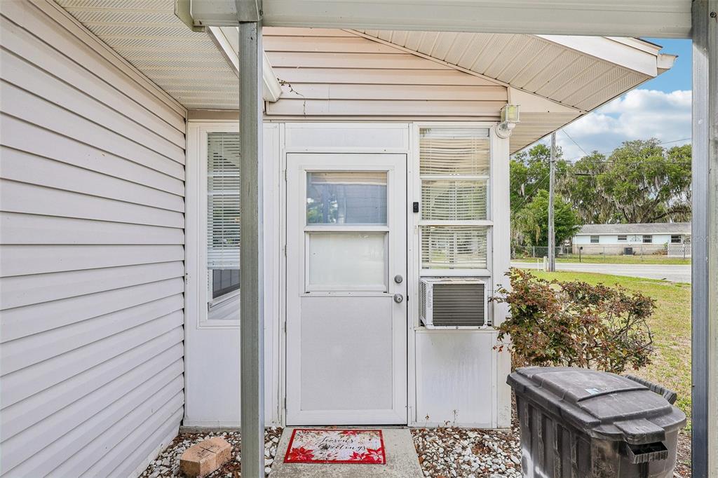 A white exterior door with a window sits between two windows under a covered porch — 931 CR 457A, LAKE PANASOFFKEE, FL