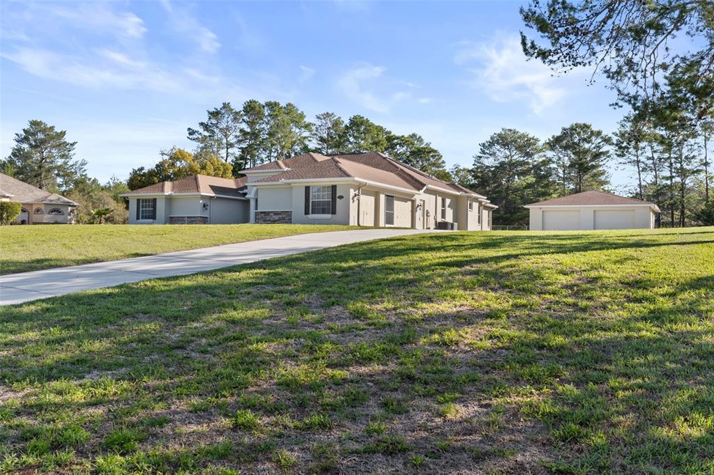 A single-story house with a concrete driveway and a detached garage on a grassy lot — 10130 LAZY DAYS COURT, WEEKI WACHEE, FL