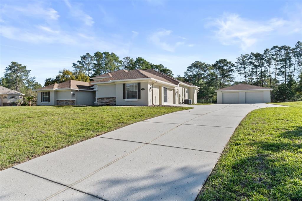 A single-story house with a concrete driveway and a detached two-car garage — 10130 LAZY DAYS COURT, WEEKI WACHEE, FL