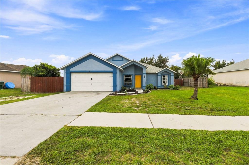 A blue single-story house with a yellow front door and a two-car garage — 677 SAGAMORE DRIVE, DELTONA, FL