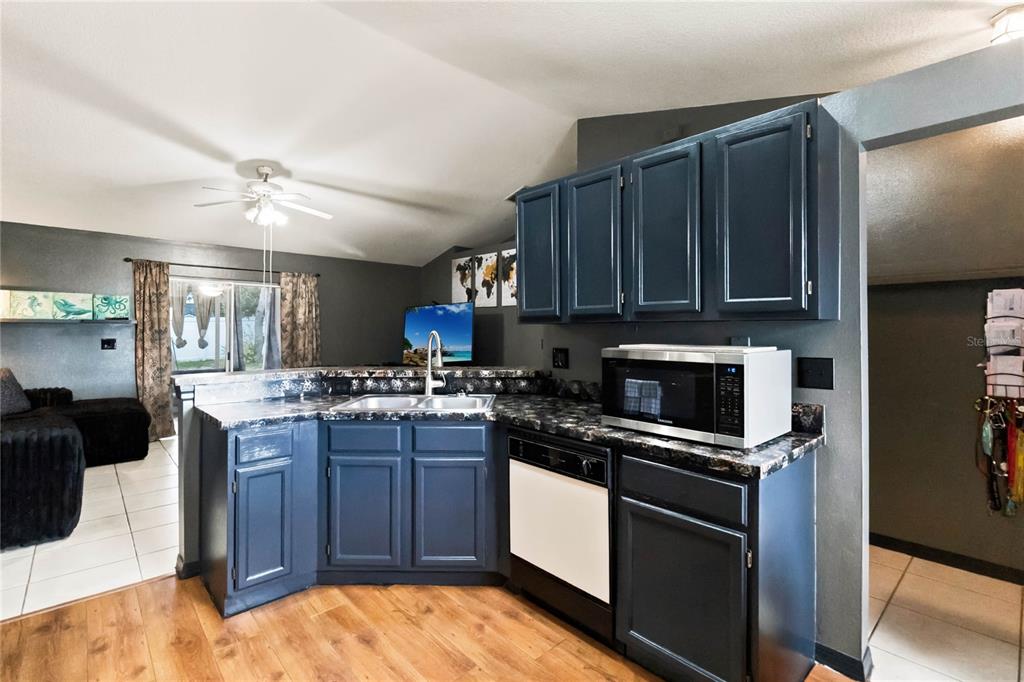 A kitchen features dark blue cabinets, a black and white countertop, and a stainless microwave — 677 SAGAMORE DRIVE, DELTONA, FL