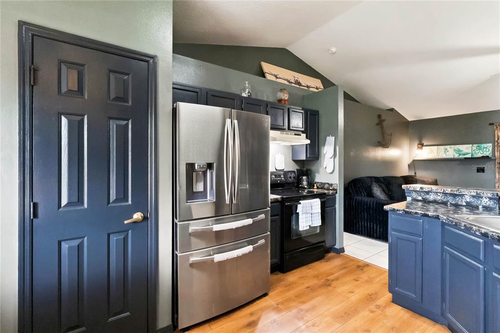A kitchen with dark blue cabinets, stainless steel appliances, and wood-look flooring — 677 SAGAMORE DRIVE, DELTONA, FL