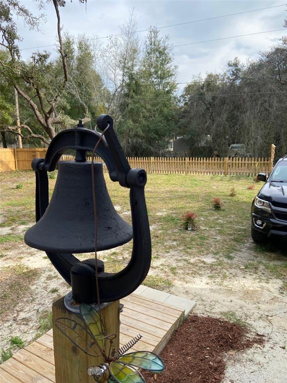 A black decorative bell sits on a wooden post in a yard with a picket fence — 11743 PURDUE STREET, NEW PORT RICHEY, FL