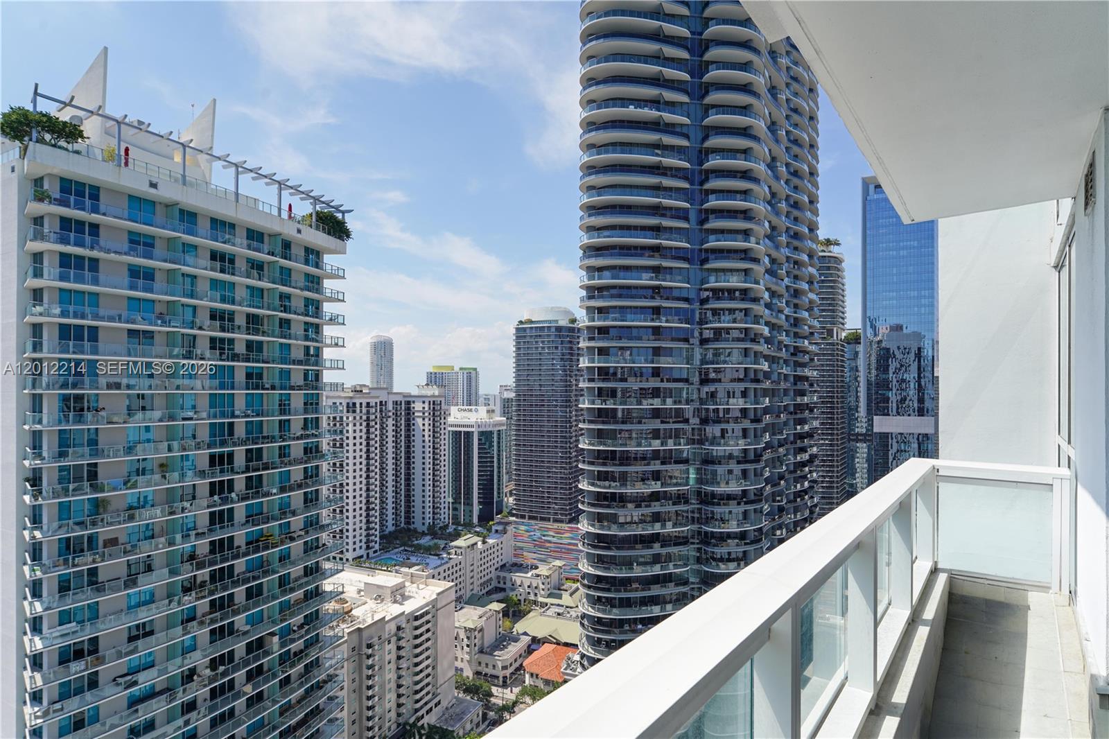 A balcony overlooks a dense urban skyline featuring several modern high-rise residential towers — 1080 Brickell Ave # 3607, Miami FL 33131, MIAMI, FL