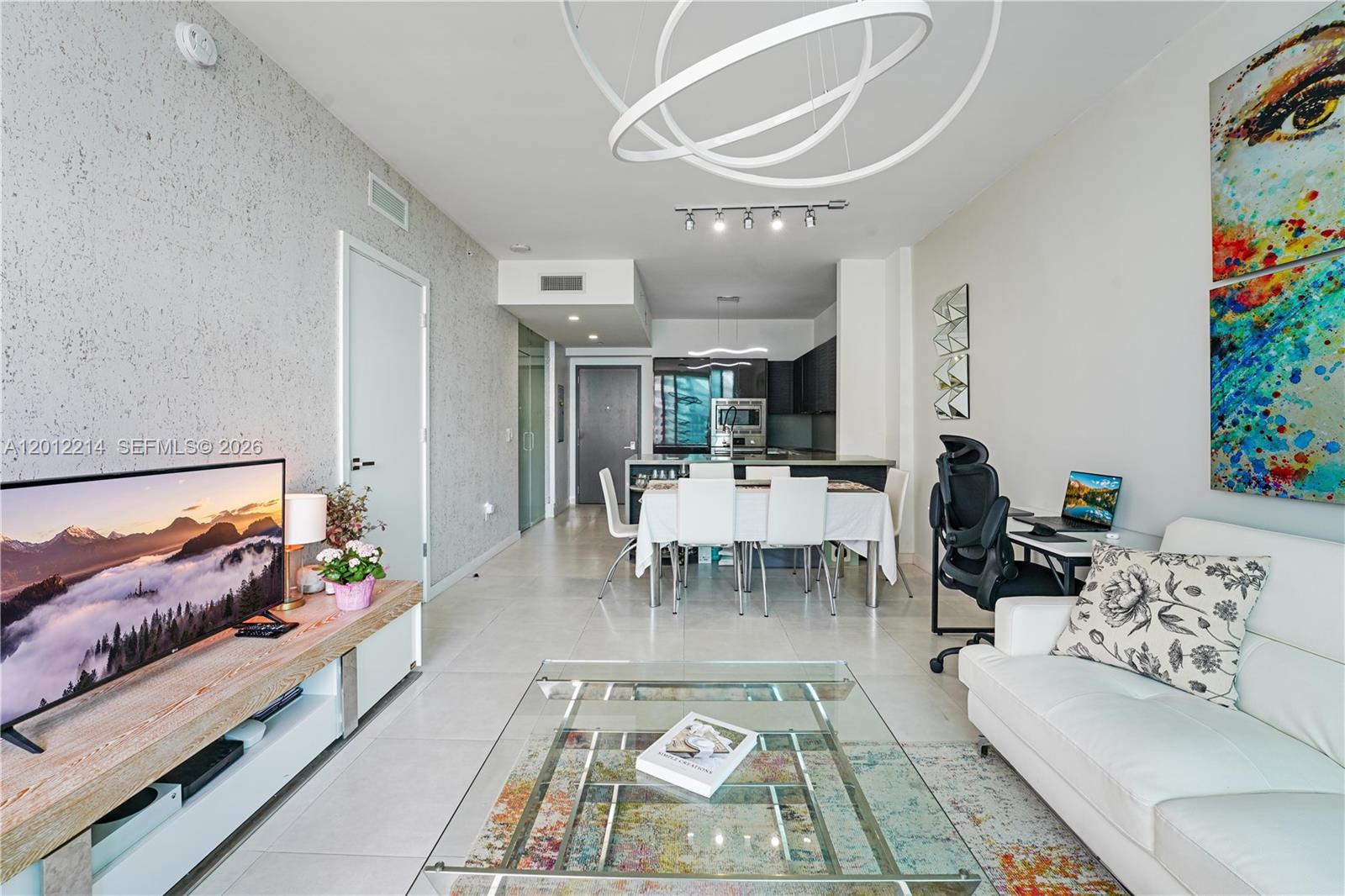 A modern living room features a glass coffee table, white sofa, dining area, and kitchen — 1080 Brickell Ave # 3607, Miami FL 33131, MIAMI, FL