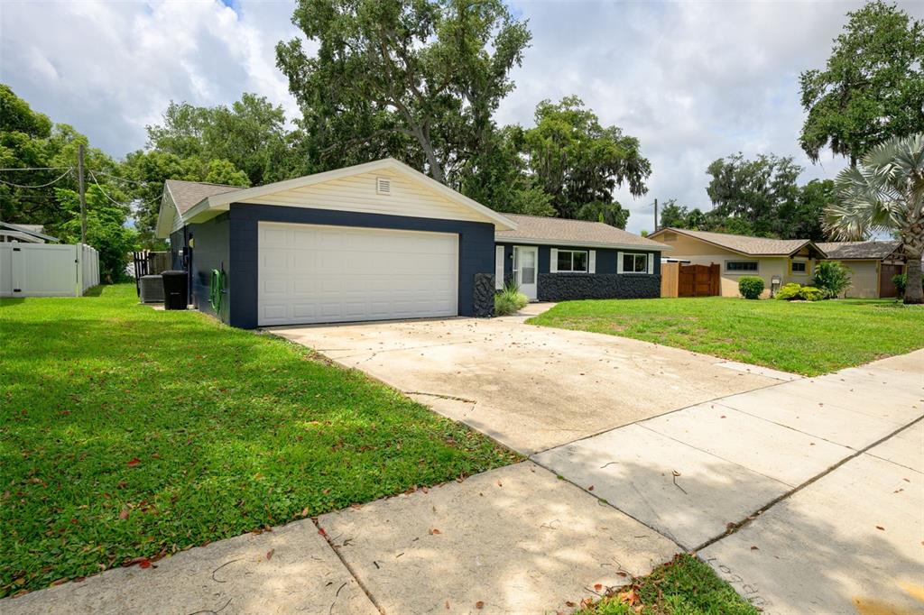 A single-story house with a blue-painted garage and exterior, a white door, and a driveway — 110 CAMBRIDGE DRIVE, PORT ORANGE, FL