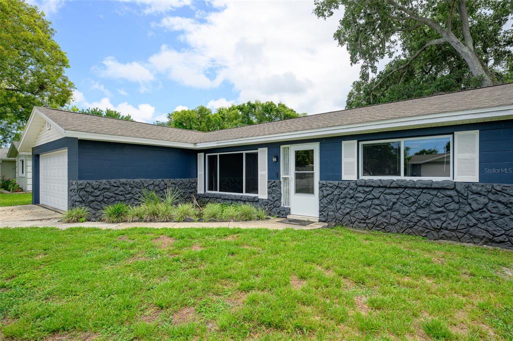 A single-story house with blue painted block walls, a stone facade, and a white garage — 110 CAMBRIDGE DRIVE, PORT ORANGE, FL