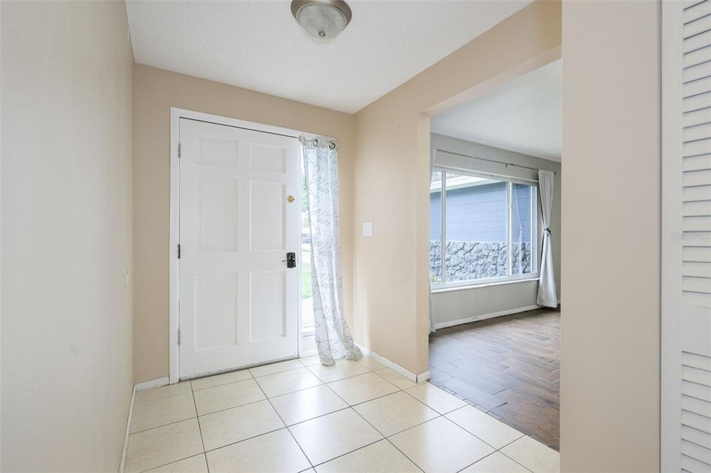 An entryway with beige tile flooring leads into a living area with wood-look floors — 110 CAMBRIDGE DRIVE, PORT ORANGE, FL