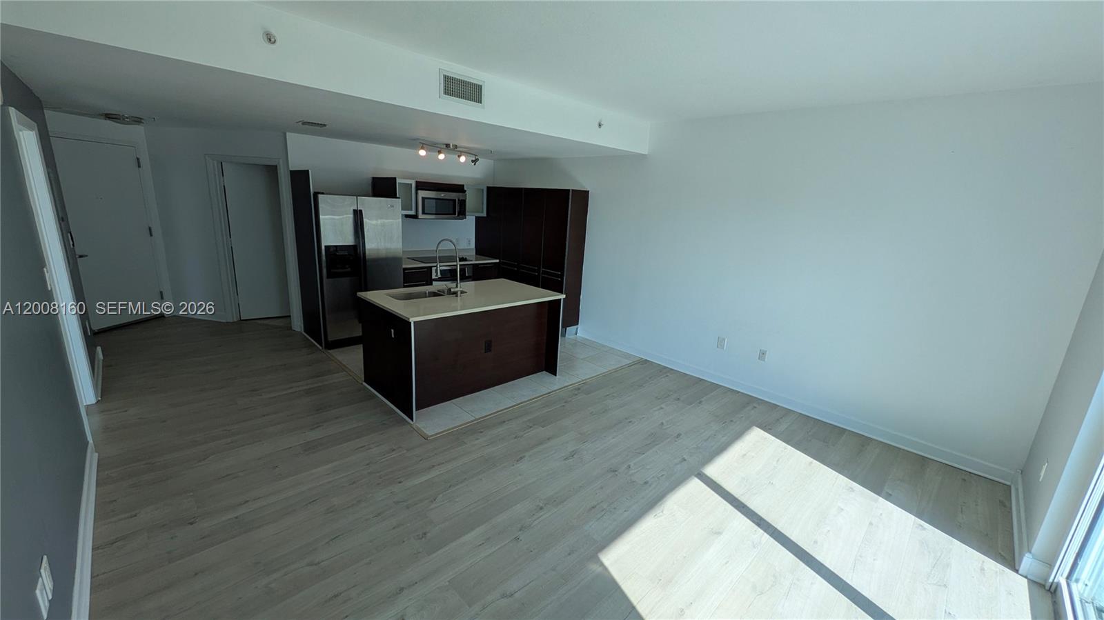 An open-concept kitchen with a central island, dark cabinetry, and light wood-look flooring — 1900 N Bayshore Dr # 4007, Miami FL 33132, MIAMI, FL