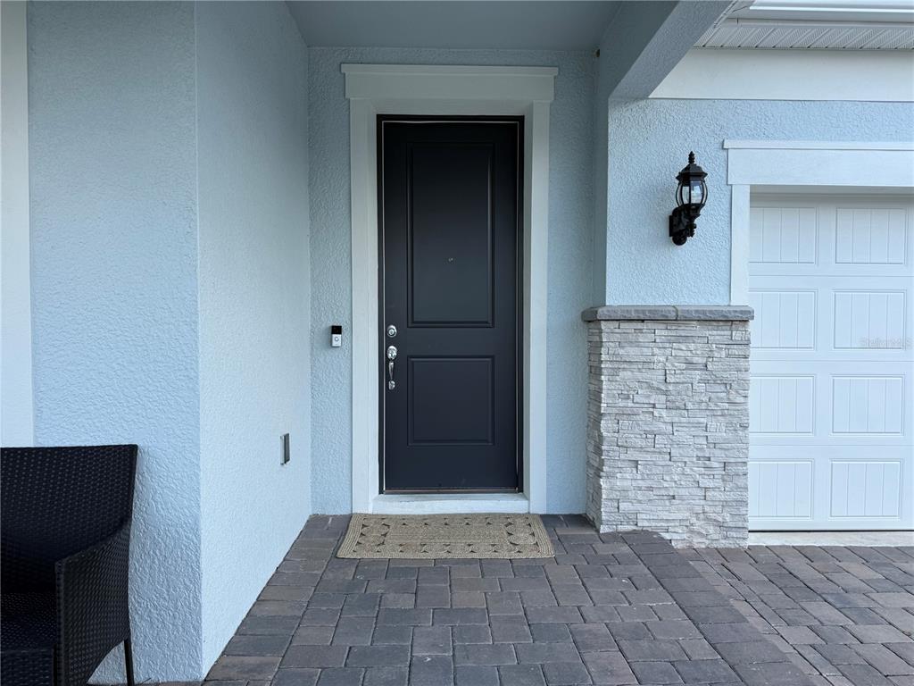 A dark front door with a stone-accented wall and a paved entryway — 3329 ORANGE ROSE LOOP, APOPKA, FL