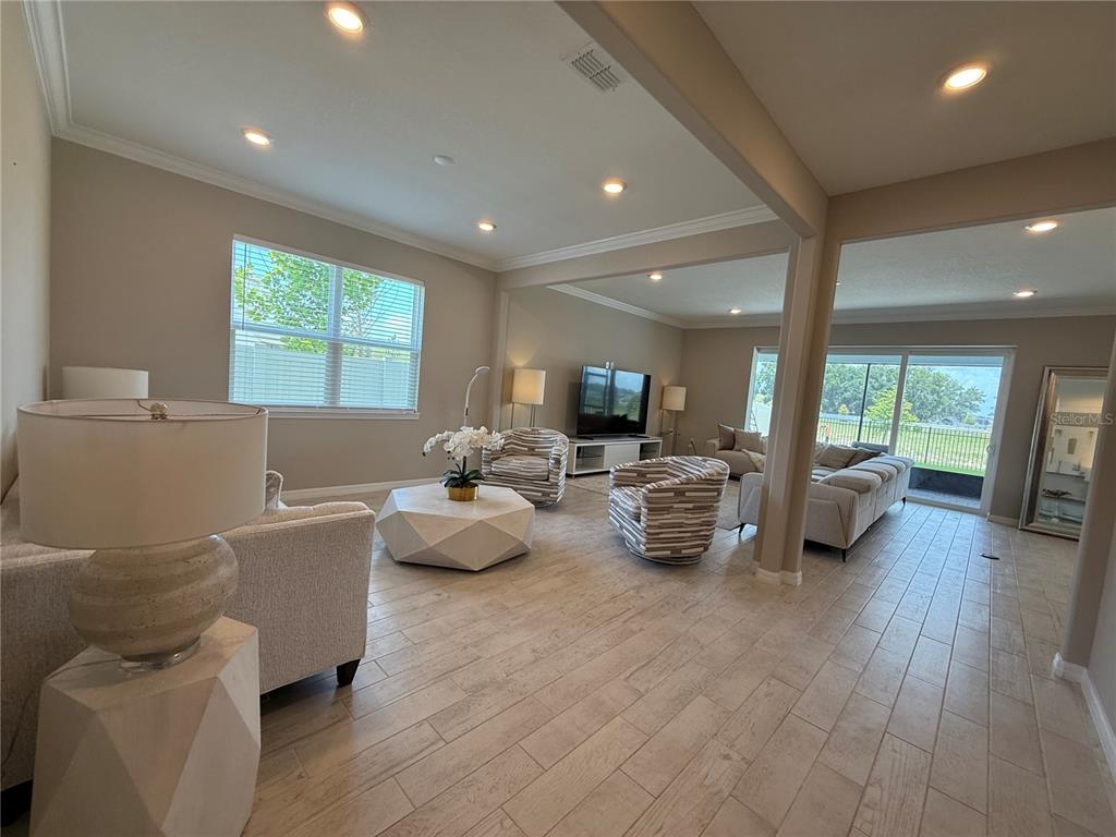 A spacious living room features tile flooring, neutral walls, recessed lighting, and large sliding glass doors — 3329 ORANGE ROSE LOOP, APOPKA, FL