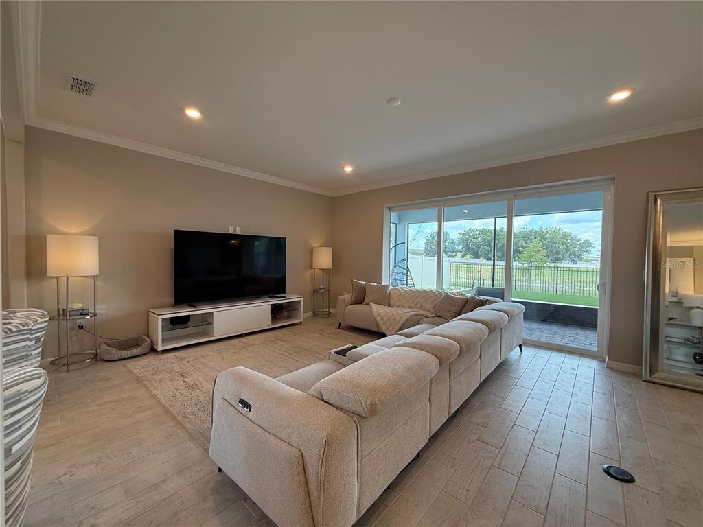 A living room features a large sectional sofa, a television console, and sliding glass doors — 3329 ORANGE ROSE LOOP, APOPKA, FL