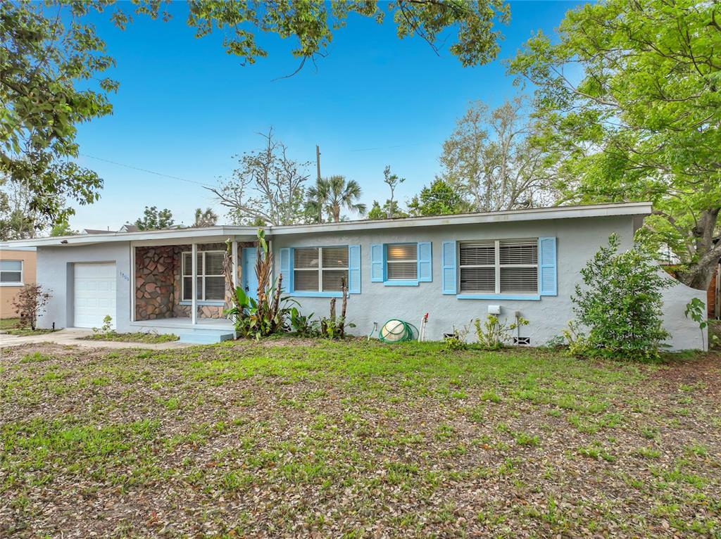 A single-story house with light blue stucco, blue shutters, and a stone-accented front porch — 1700 EDMUNDSHIRE ROAD, ORLANDO, FL