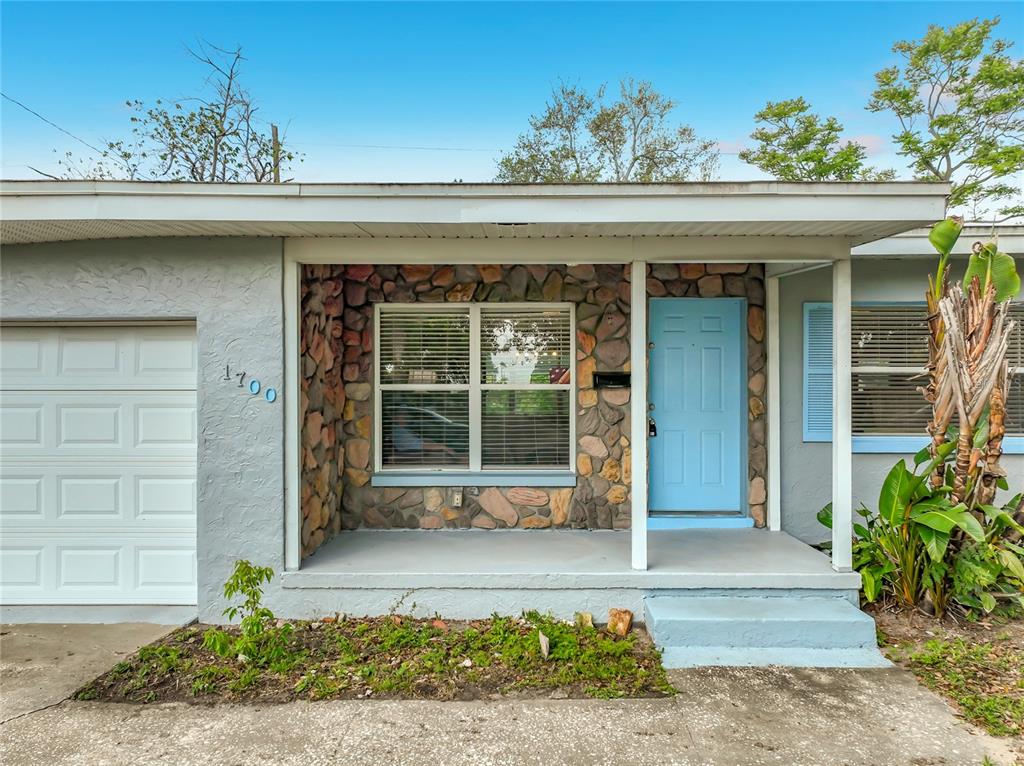 The exterior of a single-story house features a stone facade, a blue door, and a garage — 1700 EDMUNDSHIRE ROAD, ORLANDO, FL
