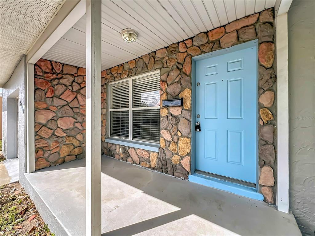 A covered front porch features a light blue door and a stone-veneer exterior wall — 1700 EDMUNDSHIRE ROAD, ORLANDO, FL