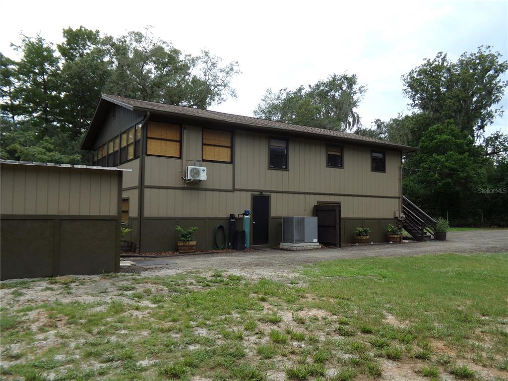 The exterior of a two-story house with brown siding and a gravel driveway — 33068 ROUND TABLE ROAD, DADE CITY, FL