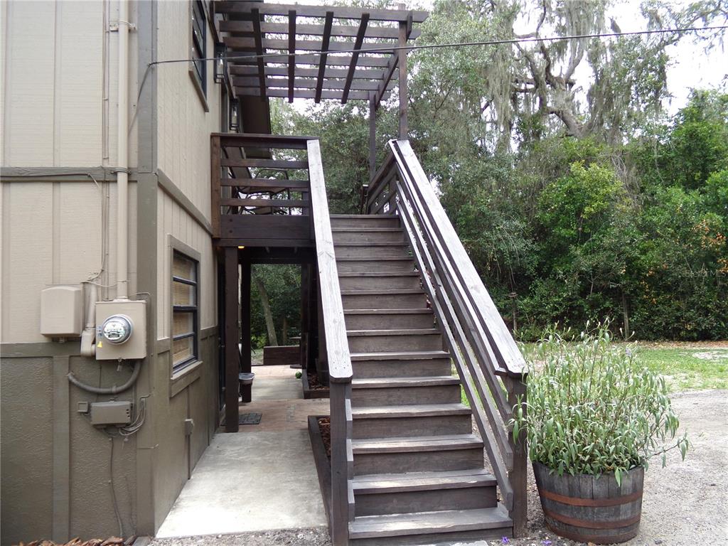 An exterior view shows a wooden staircase leading to a deck with a pergola — 33068 ROUND TABLE ROAD, DADE CITY, FL