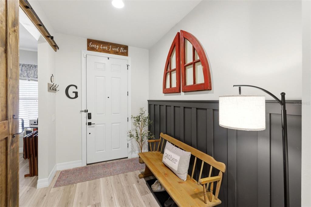 An entryway features a wooden bench, dark wainscoting, a white door, and a red window frame — 2583 MARTON OAK BOULEVARD, NORTH PORT, FL