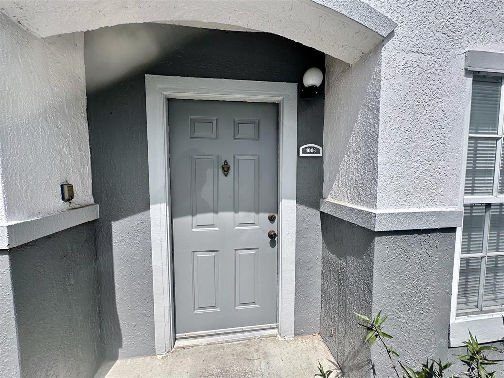The exterior view shows a gray front door with a number plate labeled 1003 — 4332 S KIRKMAN ROAD UNIT 1003, ORLANDO, FL