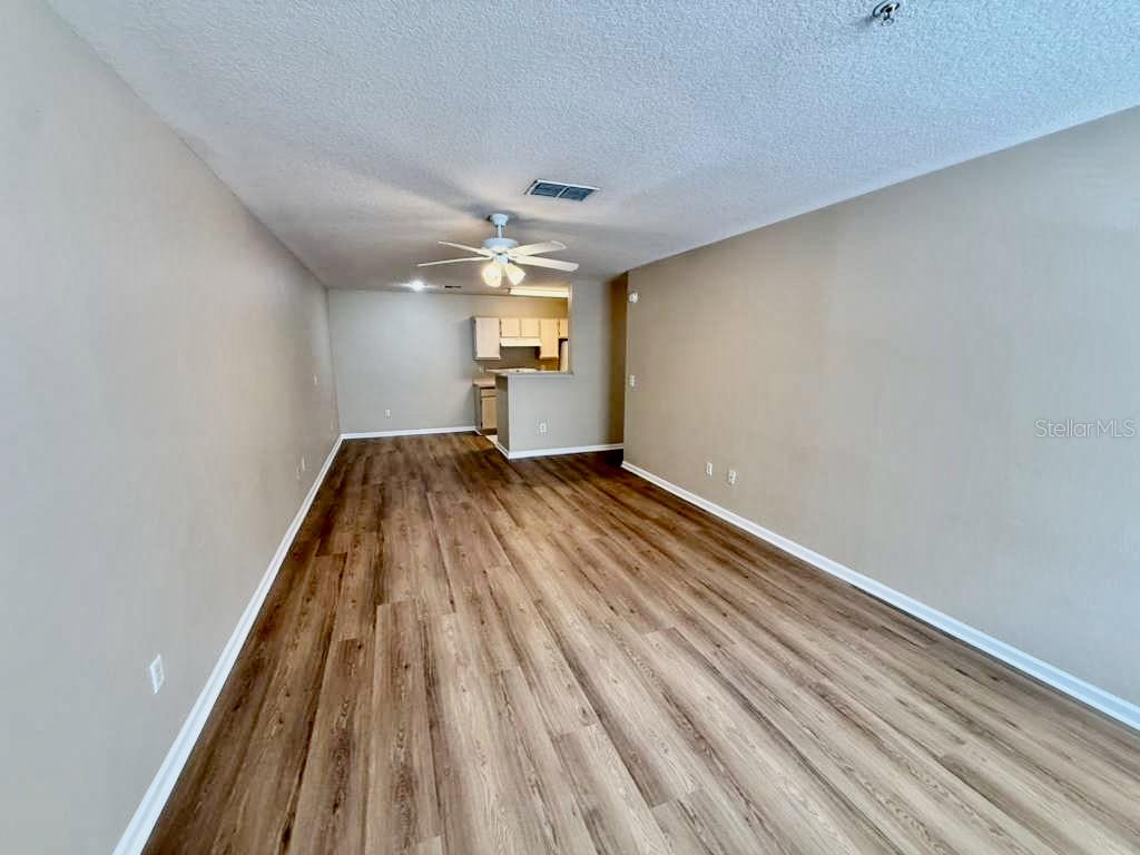 An empty living room with wood-look flooring, beige walls, and a ceiling fan — 4332 S KIRKMAN ROAD UNIT 1003, ORLANDO, FL