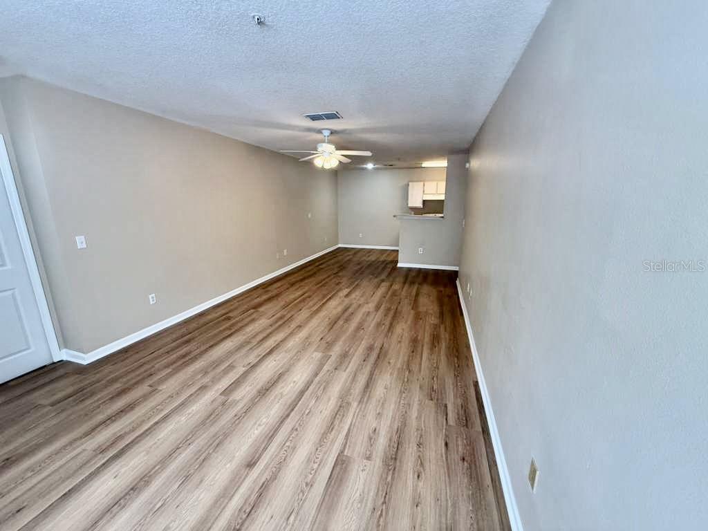 An empty living room features light-colored walls, wood-look flooring, and a ceiling fan — 4332 S KIRKMAN ROAD UNIT 1003, ORLANDO, FL