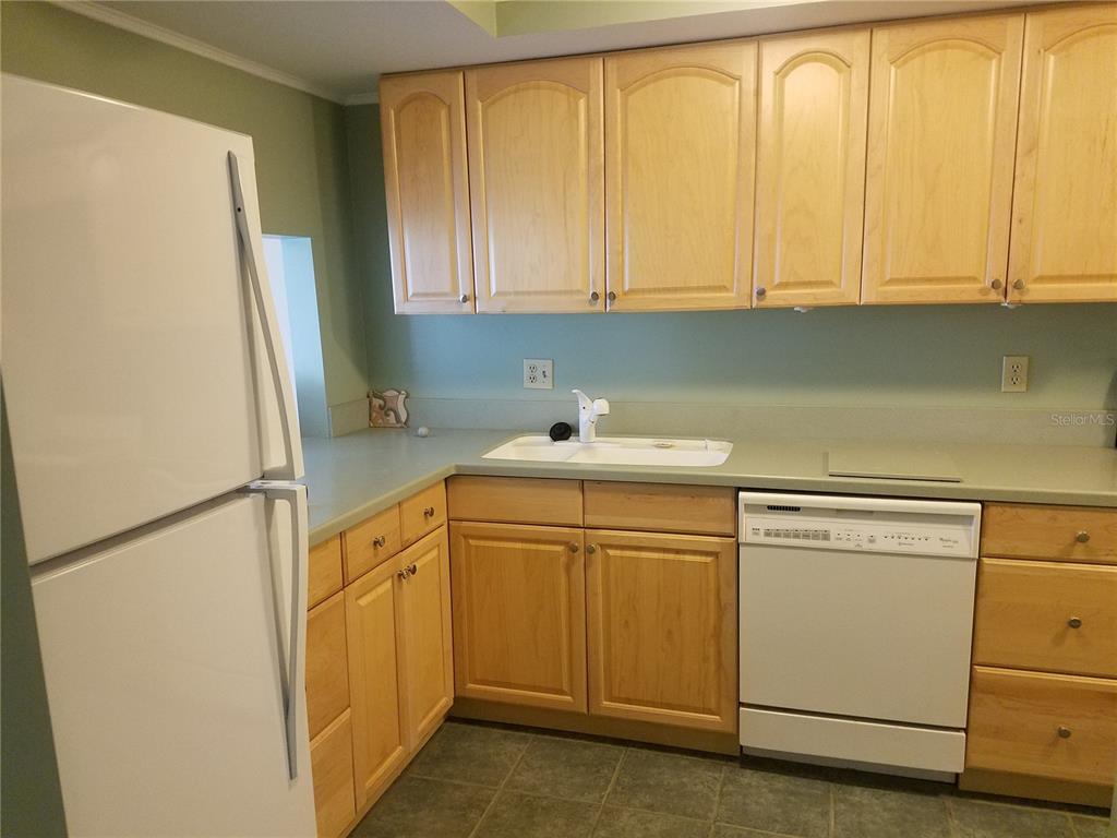 A kitchen features light wood cabinets, a white refrigerator, a white dishwasher, and green walls — 5421 VINELAND ROAD UNIT 6A, ORLANDO, FL