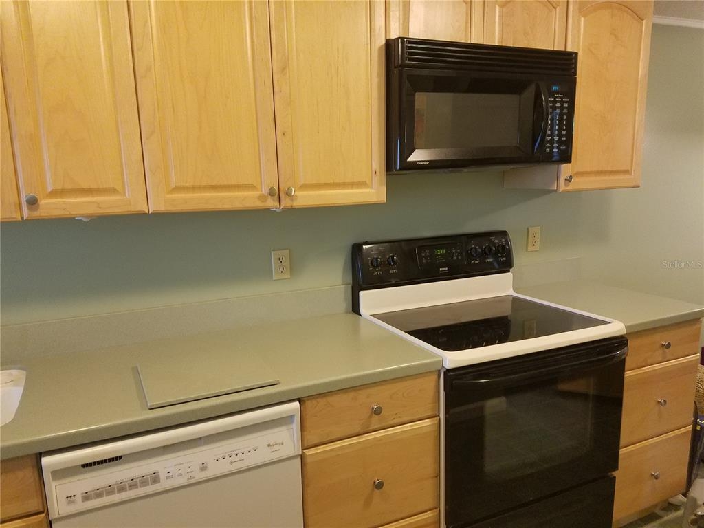 A kitchen features light wood cabinets, a black microwave, a black stove, and a dishwasher — 5421 VINELAND ROAD UNIT 6A, ORLANDO, FL