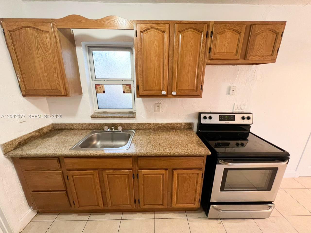 A kitchen features wood cabinets, a stainless steel sink, granite countertops, and a black stove — 3461 NW 17th St, Lauderhill FL 33311, LAUDERHILL, FL